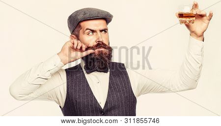 Man With Beard Holds Glass Brandy. Bearded Drink Cognac. Sommelier Tastes Drink. Man Holding A Glass