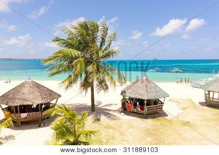 Daco Island, Philippines. Palm Trees And Bungalows On The White Sandy Beach. People Relax On A Tropi