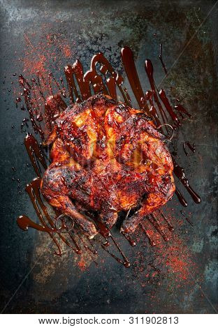 Barbecue spatchcocked barbecue chicken al mattone with hot chili sauce as top view on an old metal sheet 