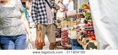 Young Pesron Choose Fresh Ripe Veggies At The Outdoor Market And Purchasing It