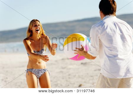 Genç bir beachball ile oynayan ve kaygısız eğlenceli bir yaz plaj tatil Çift