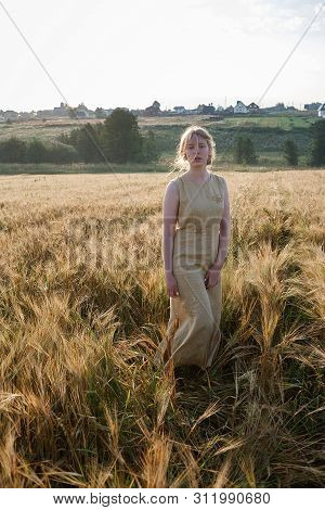 Young Pretty Girl In Yellow Vintage Outdoor Dress With Collected Hair Posing Thoughtfully, Looks At 