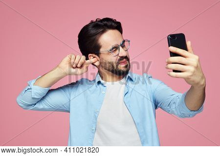 Man Un-hygienically Cleaning Ear Using Finger With Ticklish Expression While Using A Smartphone