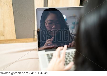 The Reflection Of Beautiful Asian Woman From Laptop Screen. She Plays Laptop And Lays On The Bed In 