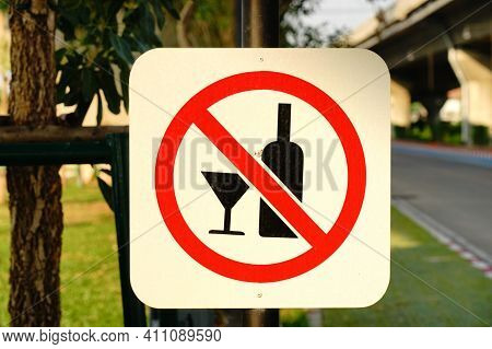 Glass With An Alcoholic Drink, Against The Background Of Bottles With Alcohol. Alcohol Addiction. Ha
