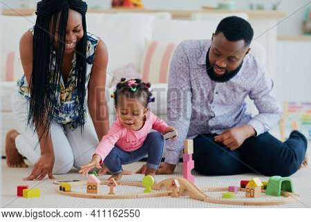 Happy Family With Toddler Baby Playing Toy Railway Together At Home