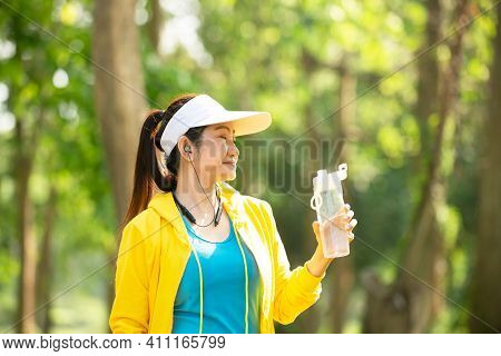 Healthy Athletic Woman Drinking Pure Water After Go Running To Be Fresh In The Nature Park. Asian Ru