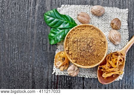 Nutmeg Round In Bowl And Mace In Spoon On Dark Board Top