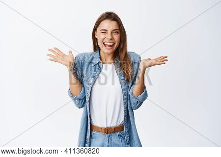 Cheerful Smiling Woman Shrugging Shoulders As If Know Nothing And Winking At Camera, Feeling Silly, 