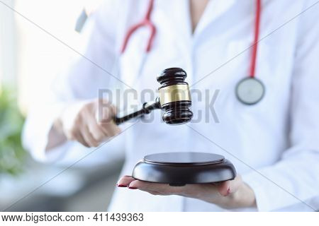 Medical Officer In White Coat Holds Wooden Gavel For Judge. Medical Litigation Concept