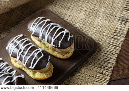 Eclairs With Black Chocolate And White Chocolate With Custard On Rustic Table. Traditional French De