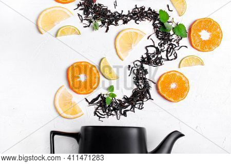 Dry Tea Leaves, Tangerine, Orange, Lime Slices And Mint Arranged In A Wave On The White Table. Tea I