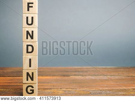 Wooden Block With The Word Funding. The Concept Of Providing Financial Resources To Organizations An