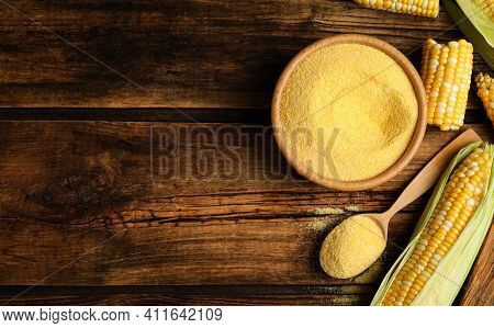 Flat Lay Composition With Cornmeal And Fresh Cobs On Wooden Table, Space For Text