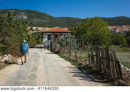 Hiking Lycian way. Man is trekking through Bezirgan village on Lycian Way trail along old broken ragged fence, Outdoor activity in Turkey