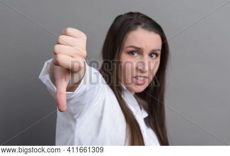 1 White Young Woman In A White Shirt Shows A Sign With Her Finger Down, Bad On A Gray Background