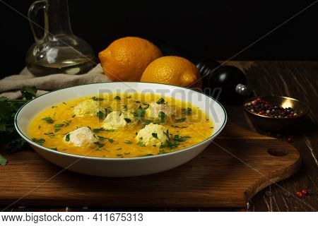 Avgolemono, Greek Chicken Soup With Meatballs, Lemons, Rice And Egg Yolks. Close-up On A Wooden Boar