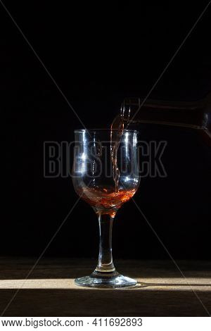 Homemade Red Wine Is Poured Into A Glass On A Dark Background. Glass Of Red Wine On A Black Backgrou