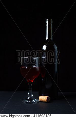 A Glass Of Homemade Wine Next To A Bottle On A Dark Background. Glass Of Red Wine On A Black Backgro