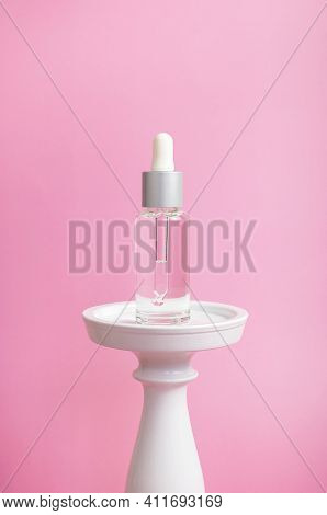 Face Serum With Pipette In Glass Bottle On White Podium On Pink Background. Anti-aging Serum, Moistu