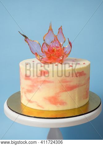 An Edible Red Isomalt Flower On Top Of A Cake On A Blue Background