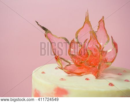 An Edible Red Flower On Top Of An Isomalt Cake On A Pink Background
