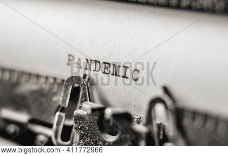Text Pandemic printed with black inks on old white paper on retro typewriter with typographic font