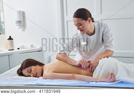Massage Practitioner Applying Deep Pressure On Back Muscles