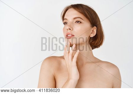 Beauty Face. Beautiful Young Woman Looking Aside And Touching Natural Healthy Skin Without Make Up. 