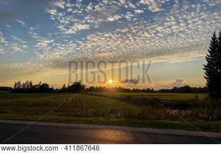 Orange Sunset Countryside With A Green Grass Field And A Visible Driveway To The House. Koku Silhoue