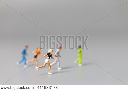 Miniature People Running On Gray Background