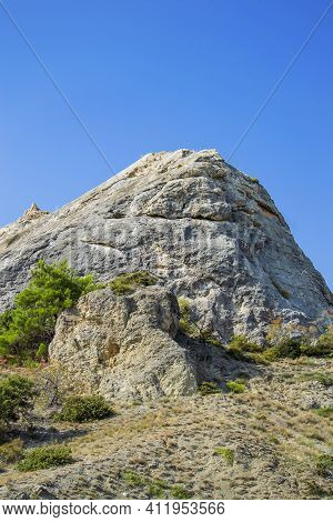 Rock And Vegetation Are Scarce In Crimea Against Clouds And Sky.