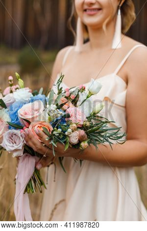 A Delicate And Very Beautiful Wedding Bouquet Of Roses, Greenery, Eustoma And Hydrangea In Brides Ha
