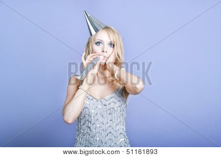 Sexy blonde party girl wearing silver dress and blowing party whistle