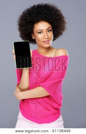 Smiling stylish sexy young African American woman with a tablet-pc holding it up to display the blank screen to the viewer