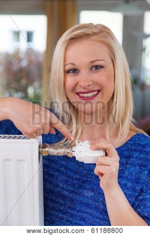 to conserve energy and electricity lowers the temperature of a young woman in the living room