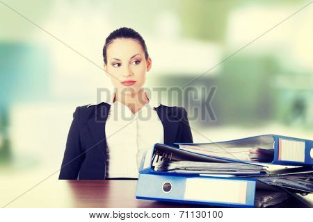 Sad woman with ringbinders sitting at the desk. Tired and exhousted business woman.
