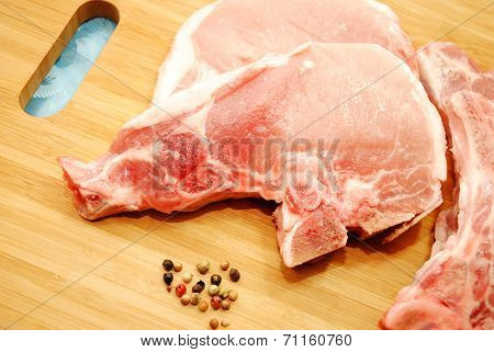 Porkchops With Whole Peppercorns On A Cutting Board