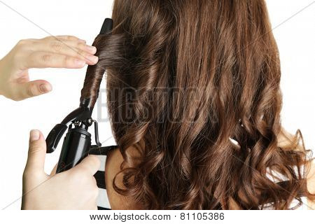 Stylist using curling iron for hair curls, close-up, isolated on white
