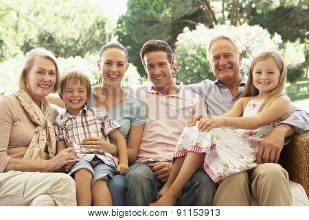 Three Generation Family Sitting On Sofa Together