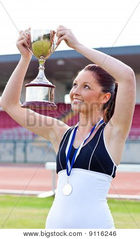 Gioiosa atleta femminile tiene un Trophee e una medaglia