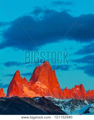 Red sunset illuminates the top of impressive cliffs Fitz Roy. Fantastic Patagonia