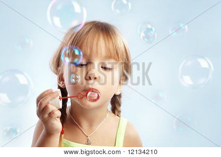Muotokuva hauska ihastuttava pikkutyttö puhaltavat saippuakuplia
