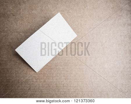 Blank cardboard business card mockup on kraft hardboard background