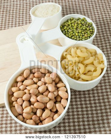 Foods High in Carbohydrate Raw Pasta Rice Peanuts and Mung Beans in Plastic Measuring Cups.