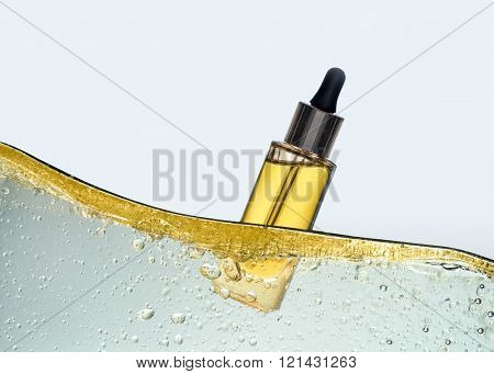 The bottle of the yellow cosmetic oil in the oil emulsion wave