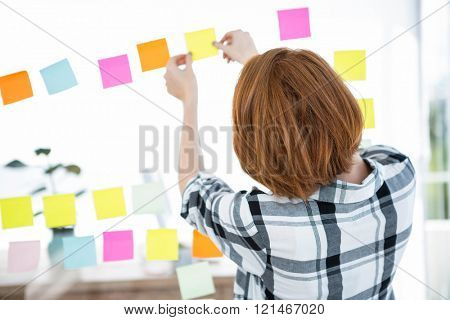 hipster woman facing away from the camera, sticking up coloured paper suares