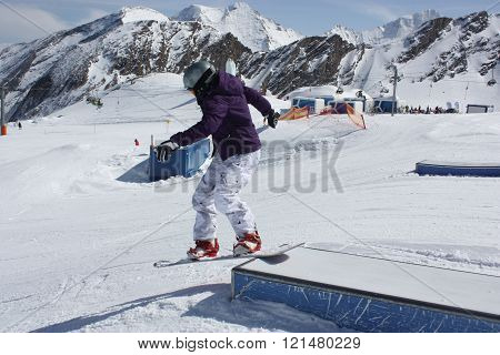Young snowboarder woman sliding on a box.