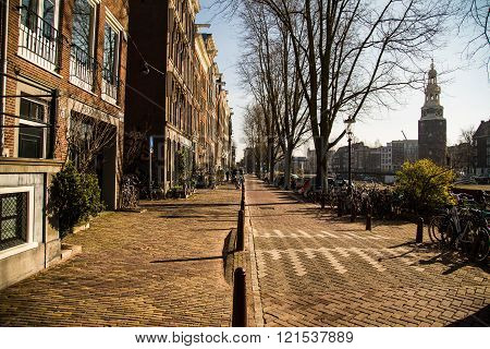 AMSTERDAM NETHERLANDS - 17TH FEBRUARY 2016: The outside of a building in Amsterdam in the morning. Bikes cars and the Montelbaanstoren Tower can be seen.
