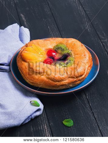 Denish fluffy bun with fruits and jelly on top a glass of mojito sliced lime towel napkin plate handmade ceramic on a dark wooden background in rustic style